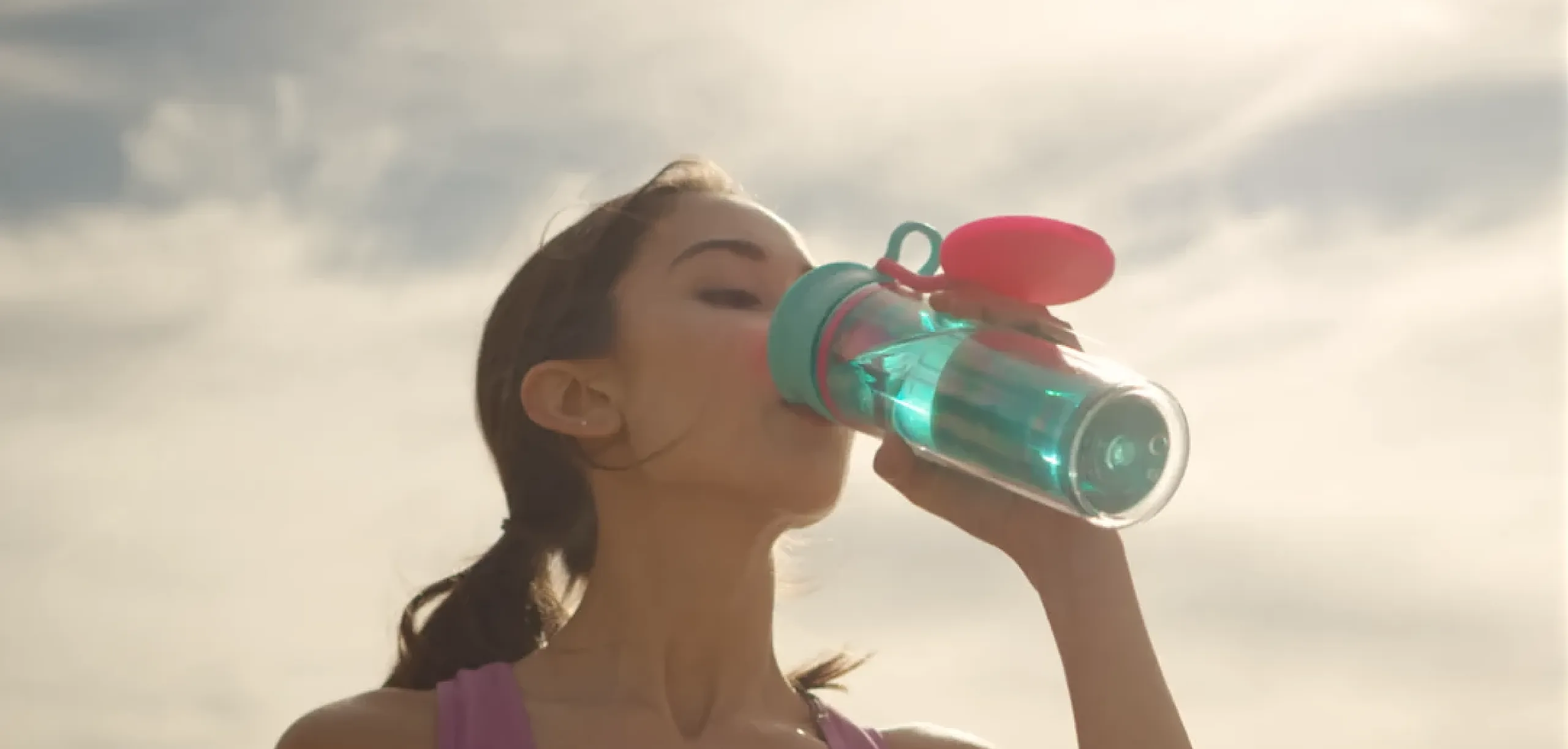 A woman drinking from the wow sports bottle